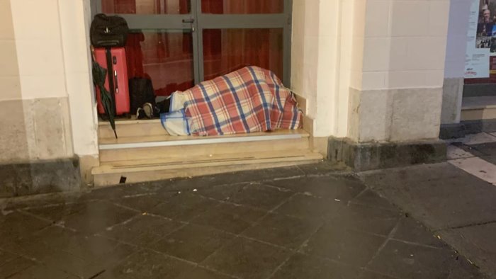 avvolto completamente in una coperta dorme su un gradone del teatro comunale